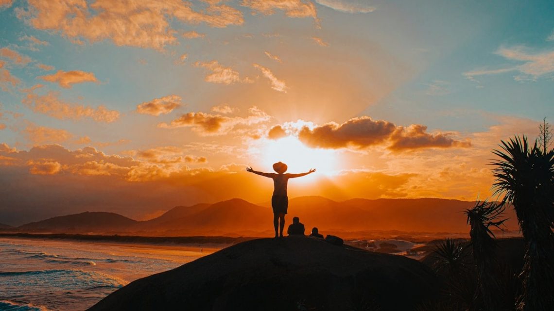 silhouette of man standing on rock formation during sunset