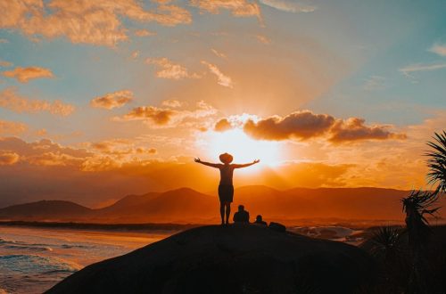 silhouette of man standing on rock formation during sunset