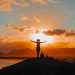 silhouette of man standing on rock formation during sunset