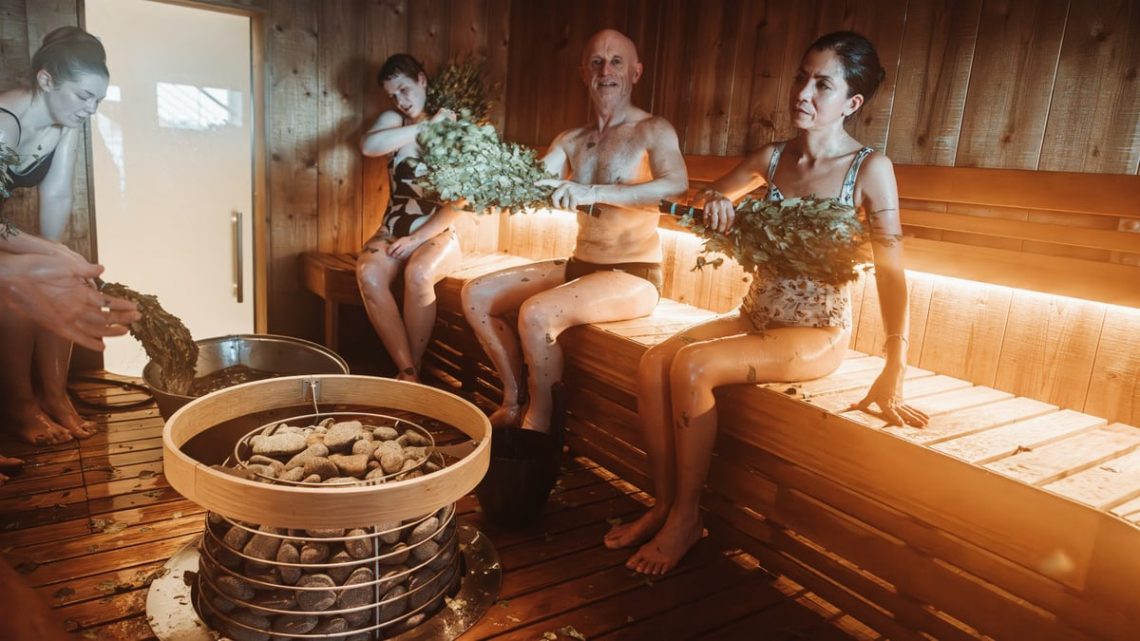 Group of people enjoying a traditional Nordic sauna with natural sauna whisking.